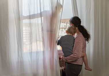 Frau mit Kind schaut aus dem Fenster