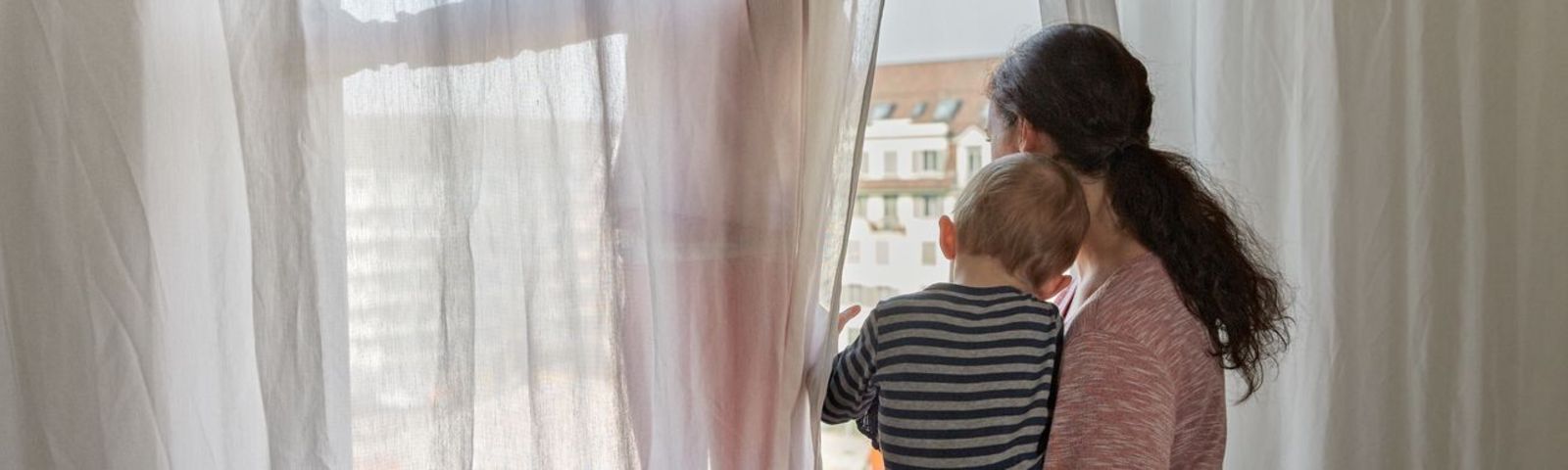 Frau mit Kind schaut aus dem Fenster