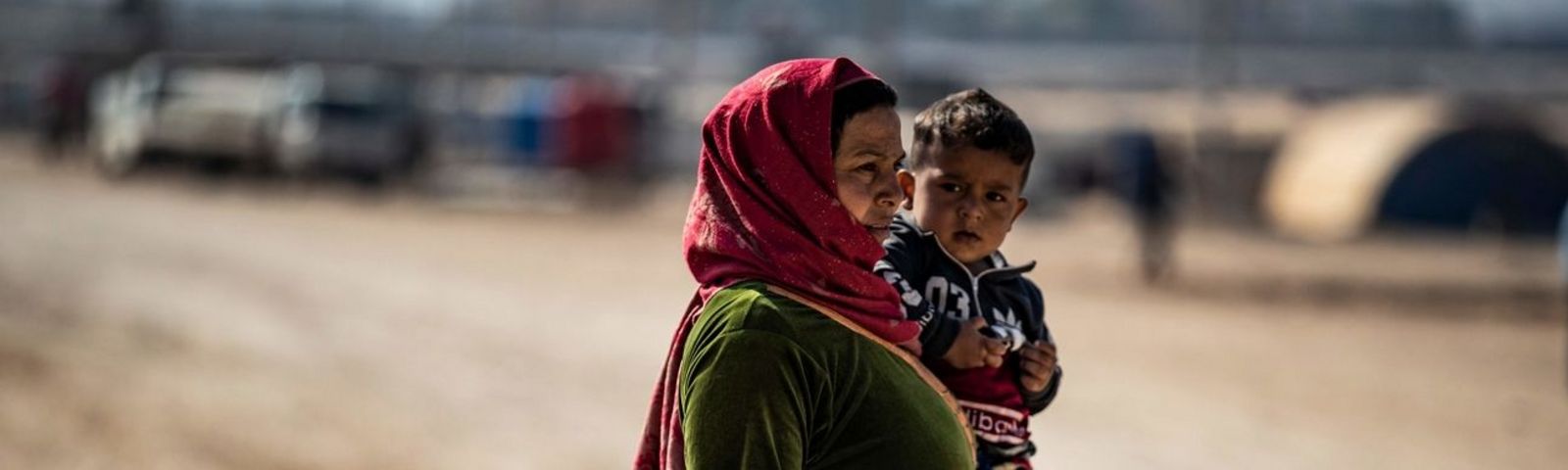 Geflüchtete Frau in einem Flüchtlingscamp hält ihr Kind im Arm
