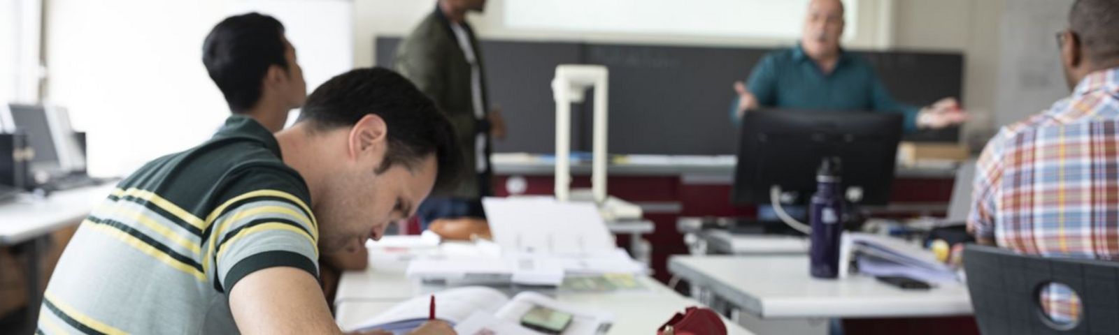 Person schreibt an einem Schultisch