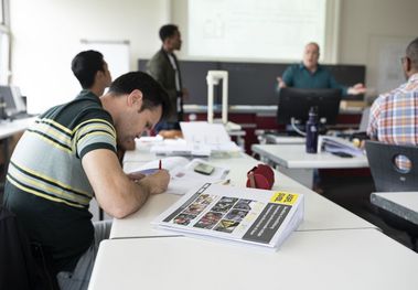 Person schreibt an einem Schultisch