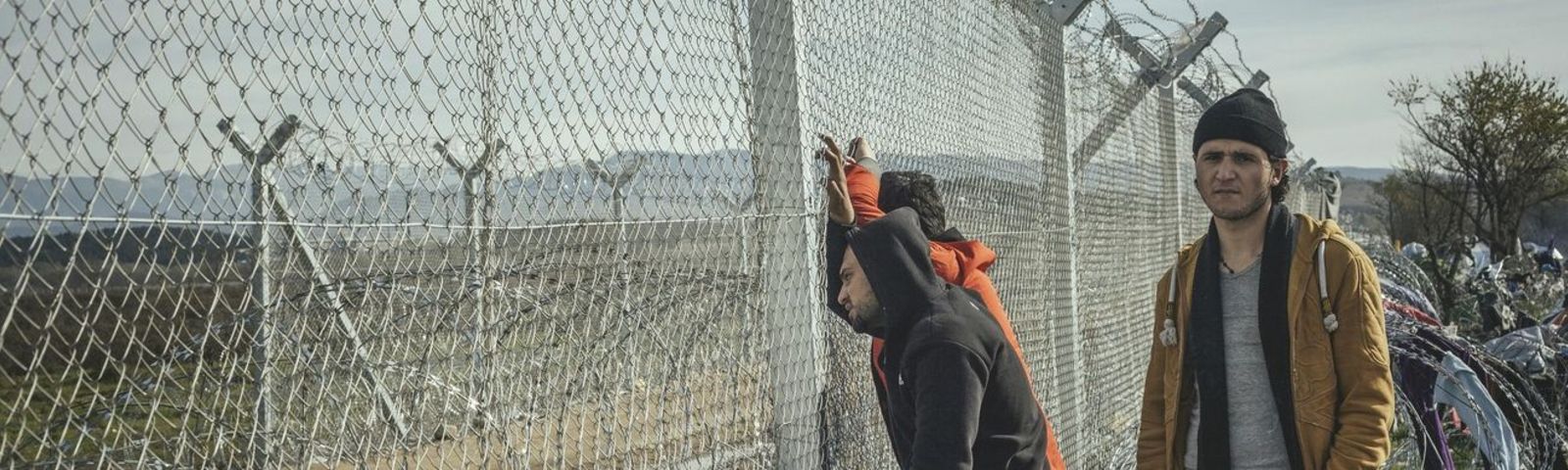 Flüchtlinge stehen an einem Zaun