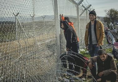 Flüchtlinge stehen an einem Zaun